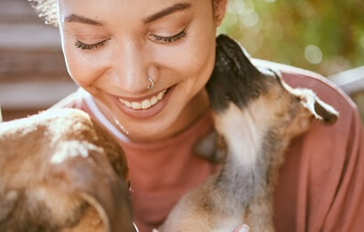 Lachende Frau wird von einem Hund aus dem Tierschutz abgeleckt